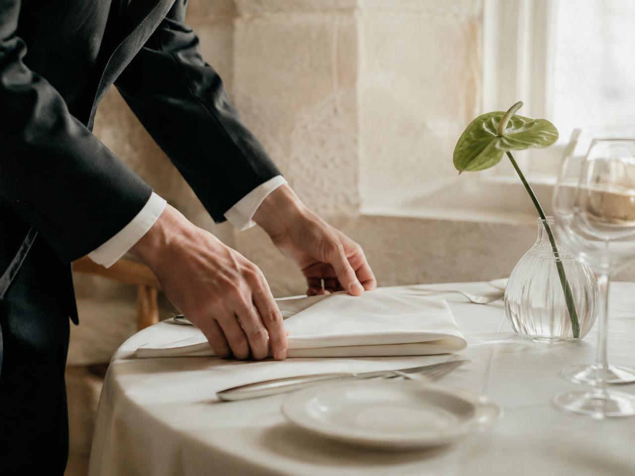 Hospitality professional preparing an elegant dining table